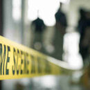 Crime,scene,tape,with,blurred,forensic,law,enforcement,background,in